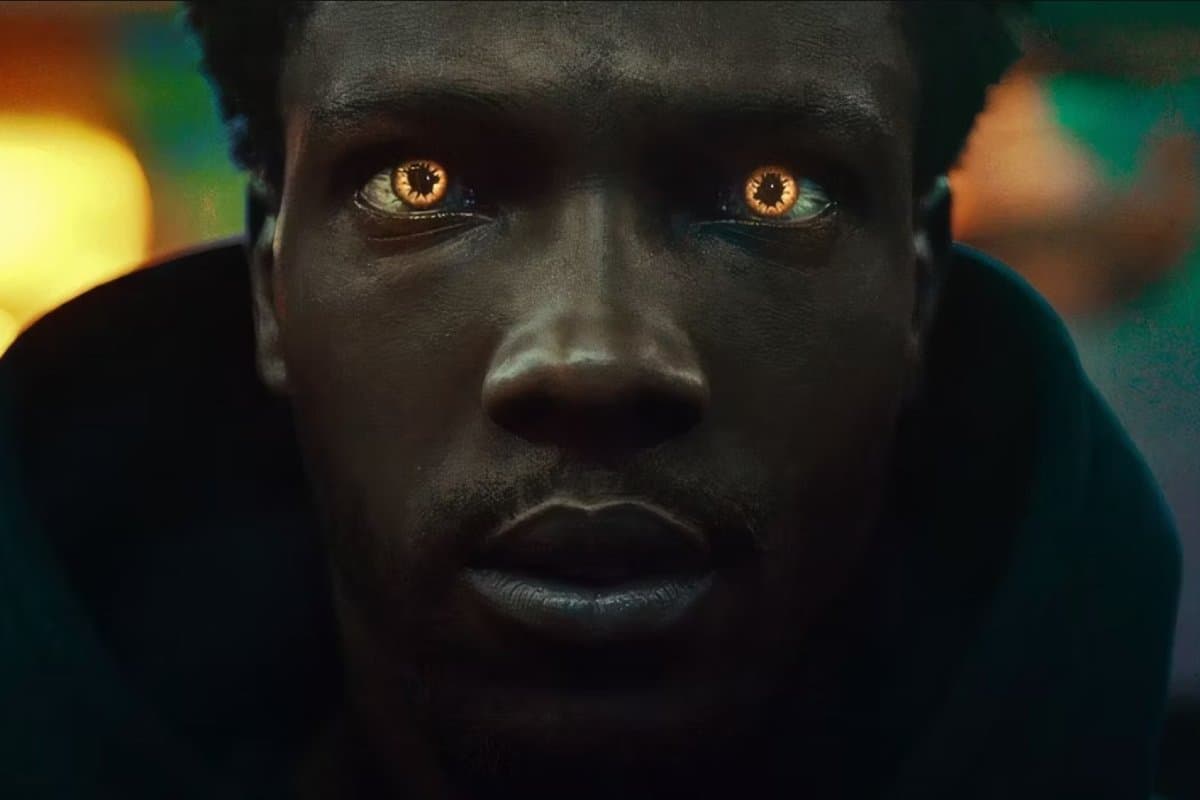 an african english man with glowing orange eyes stares at the camera