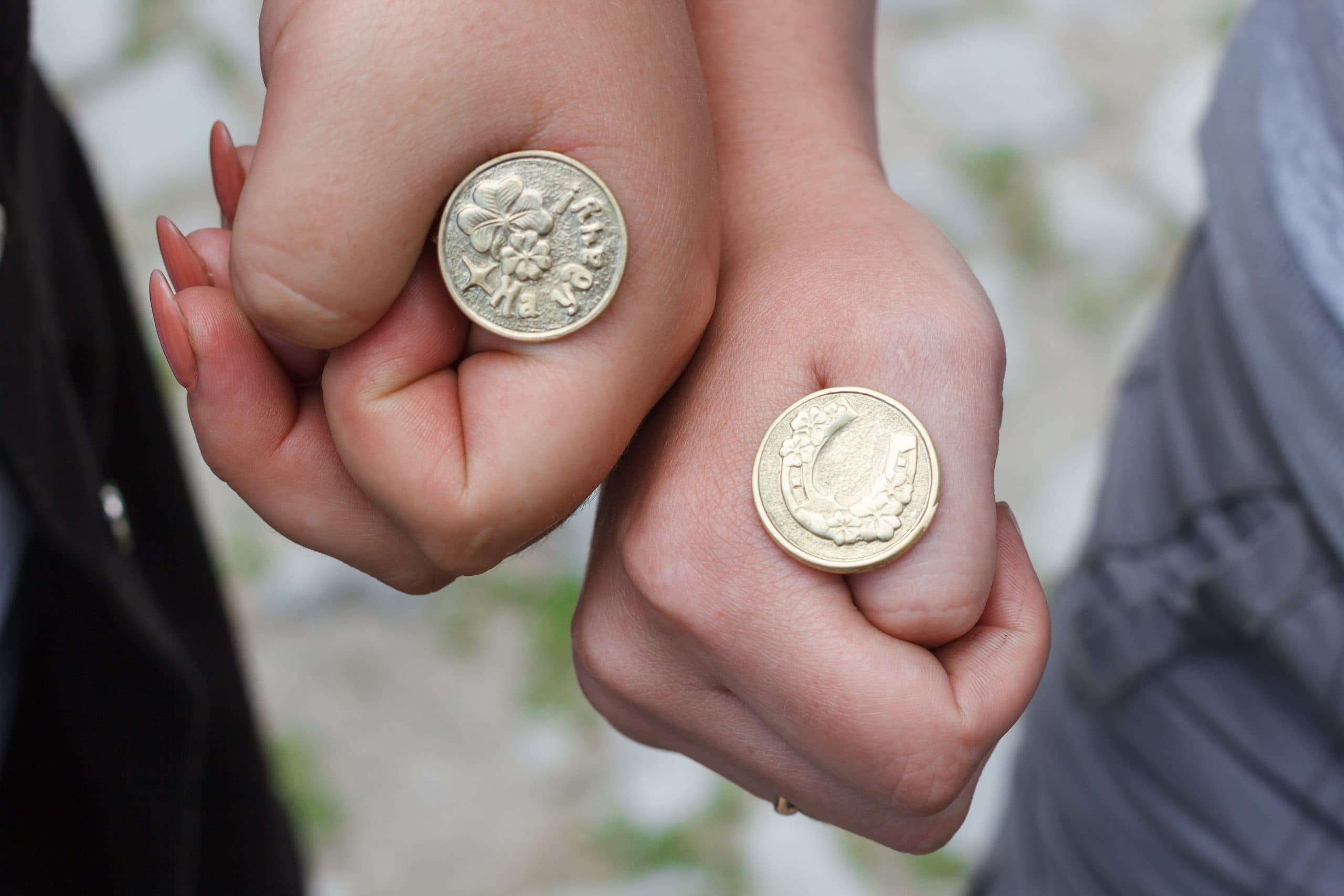 Hands of two people together with coins on their first, ready to flip.