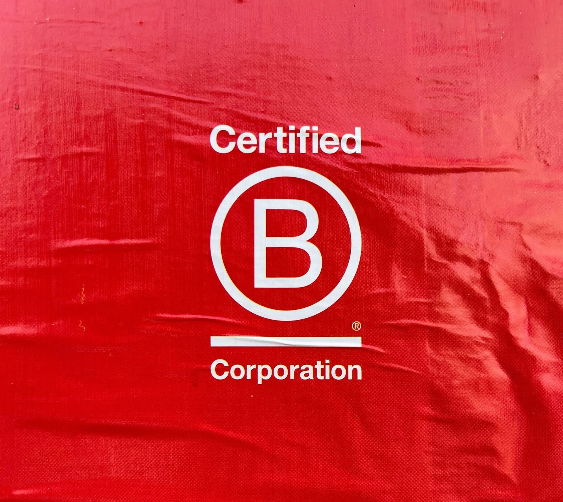 White B Corp certification logo on red textured background
